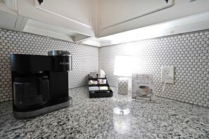 Eine moderne Küche mit einer schwarzen Keurig-Kaffeemaschine, einem Kapselhalter und einem Schild mit der Aufschrift 'Kaffeeliebhaber sind die besten Menschen.'