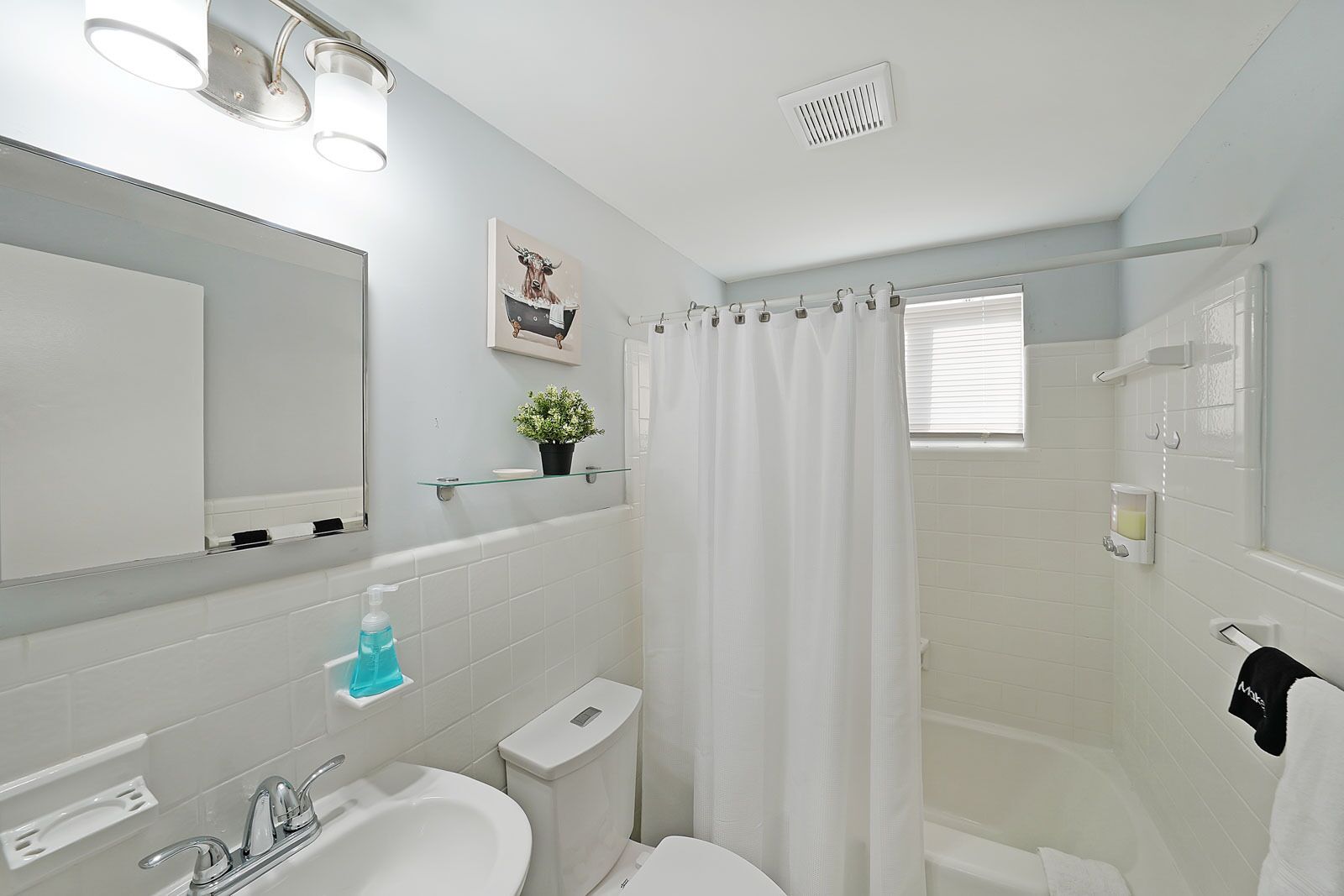 A modern bathroom with a white sink, mirror, and shower area.