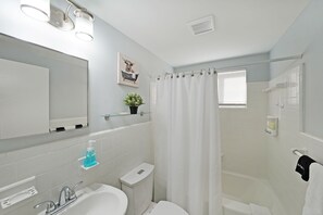 A modern bathroom with a white sink, mirror, and shower area.