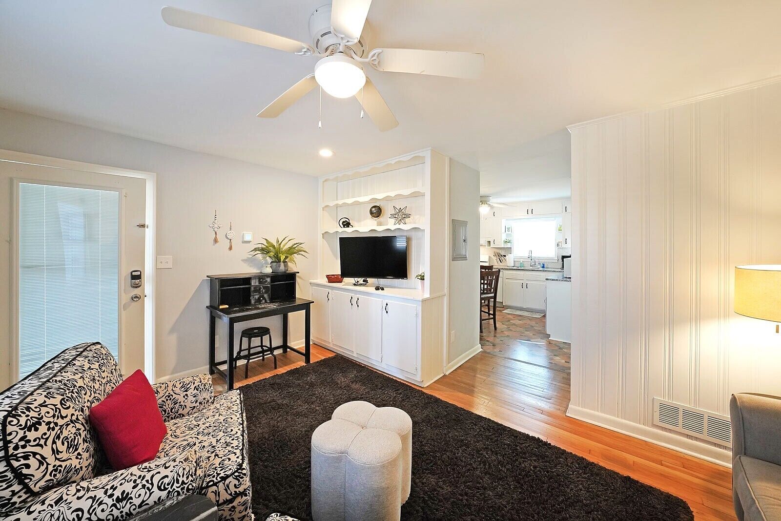 A modern living room with a sofa, a coffee table, a TV, and a ceiling fan.