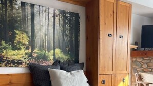 Un dormitorio con una cama grande, un armario y un cuadro de un bosque.