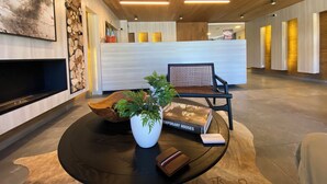 A modern lobby with a reception desk, a seating area with a plant and a book, and a wooden ceiling. - Coastal apartment with lake view, heated swimming pool and jacuzzi (Puerto Varas)