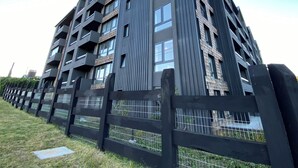 A modern multi-story residential building with balconies, a metal fence, and a clear sky. - Coastal apartment with lake view, heated swimming pool and jacuzzi (Puerto Varas)