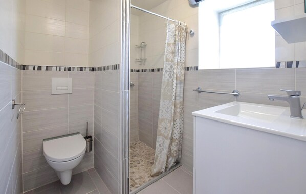 A bathroom with a toilet, shower, and sink.