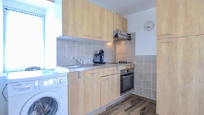 A compact kitchen with wooden cabinets, a Bosch washing machine, a coffee maker, and a clock on the wall. - Lovely apartment in Saint-Christophe-du-Fo (Saint-Christophe-du-Fo)