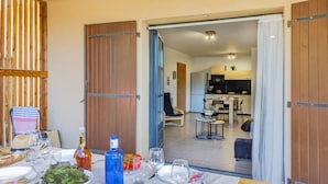 A dining area with a table set for four, a kitchen in the background, and a sliding door leading to another room. - Fiore Di Vita (Patrimonio)