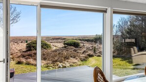A room with large sliding glass doors offering a view of a natural landscape with dry grass and bushes. - Gorgeous home in Hals with WiFi (Hals)
