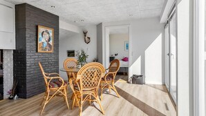 A modern living room with a fireplace, wicker furniture, and a dining area. - Gorgeous home in Hals with WiFi (Hals)