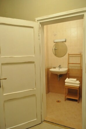A bathroom with a white door, a sink, a mirror, and a wooden shelf with towels. - ARTament
One of Sofia's most iconic spaces,  right next to the metro stop. (Sofia)