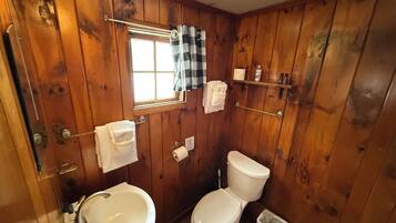 Un baño con paneles de madera, un lavabo, un inodoro y una ventana.