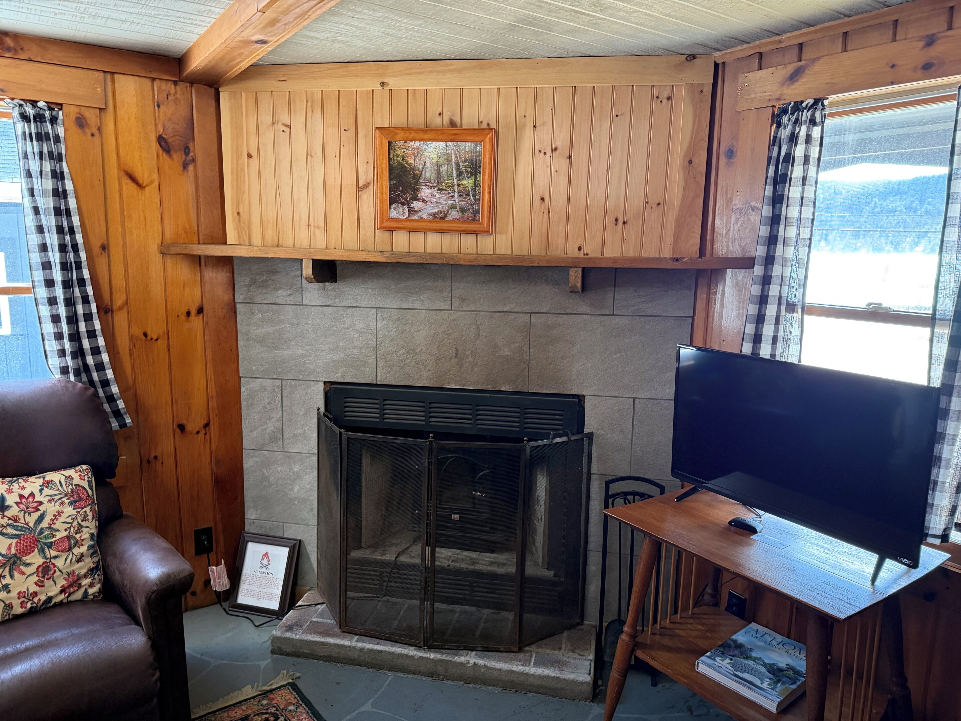 Una habitación acogedora con chimenea, televisión y una ventana con cortinas.