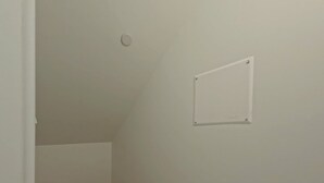 A room with a sloped ceiling, a light switch, and a whiteboard on the wall.