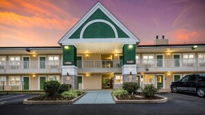 Un motel à la façade verte et blanche, doté de nombreux balcons et d’un parking.