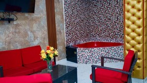 A modern bathroom with a mosaic wall, a red bathtub, and a gold tufted wall panel. - Hotel pool city  (Bonao)