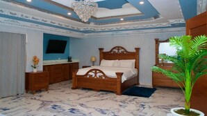A bedroom with a wooden bed, a nightstand, a dresser, a mirror, and a potted plant. - Hotel pool city  (Bonao)