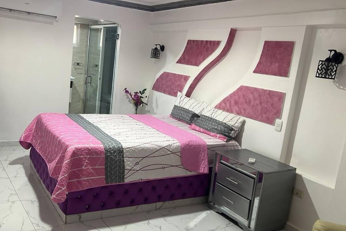 Un dormitorio con cama, armario, escritorio y ducha.