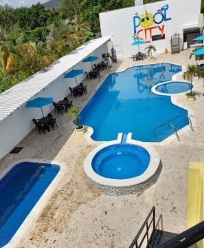 Zona de piscina amb diverses piscines, gandules i un edifici amb la inscripció "Pool City".