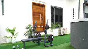 A home gym with exercise equipment, a wooden door, and potted plants. - ABOT Luxury Homes (Lekki, Lagos State)