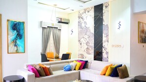 A modern living room with a sectional sofa, a coffee table with a chess set, and a large abstract painting. - ABOT Luxury Homes (Lekki, Lagos State)
