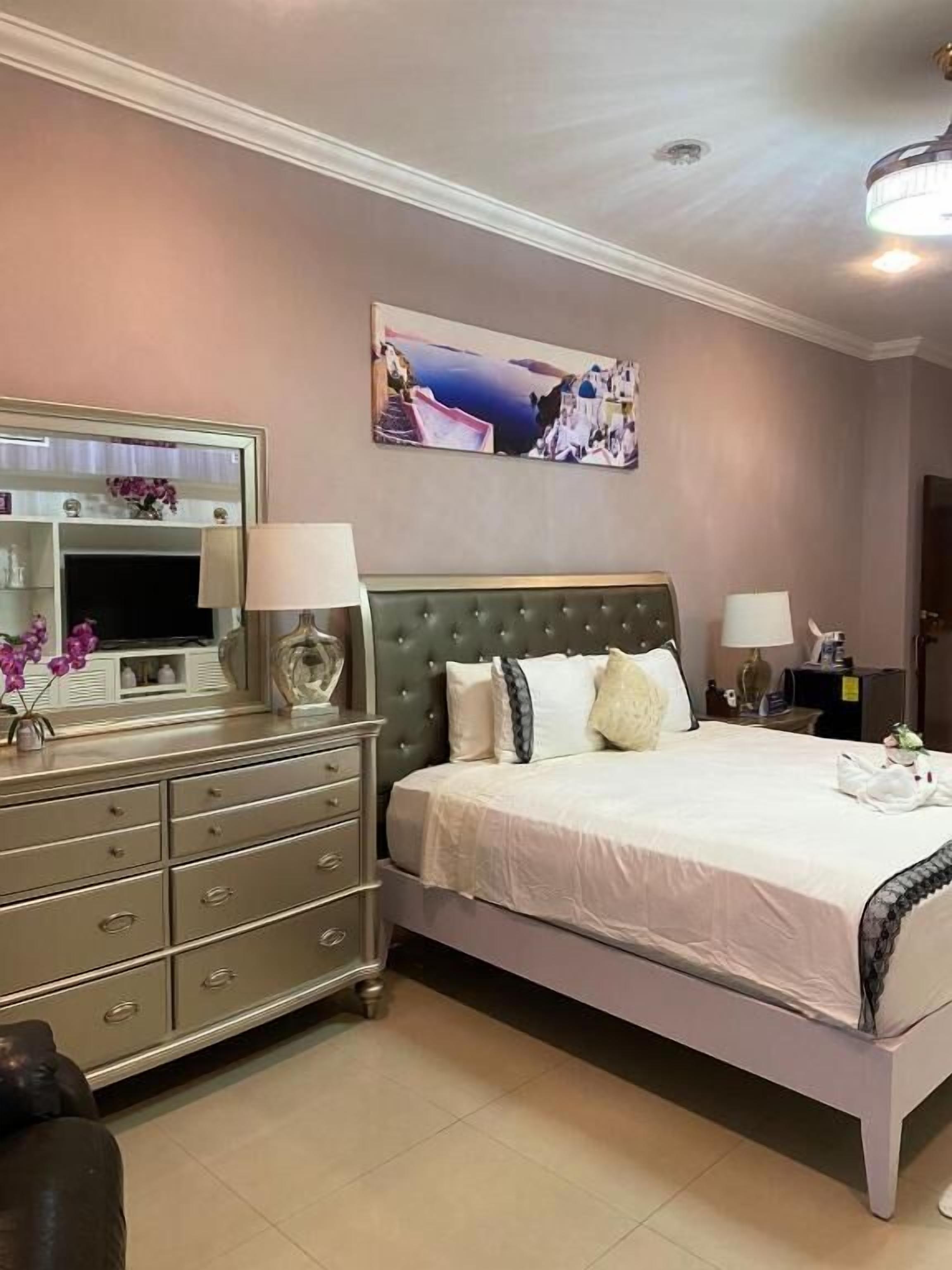 Une chambre à coucher avec un lit, une commode et un tableau accroché au mur.