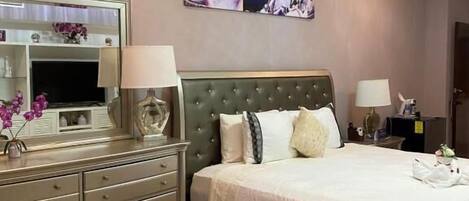 A bedroom with a bed, dresser, and a painting on the wall.