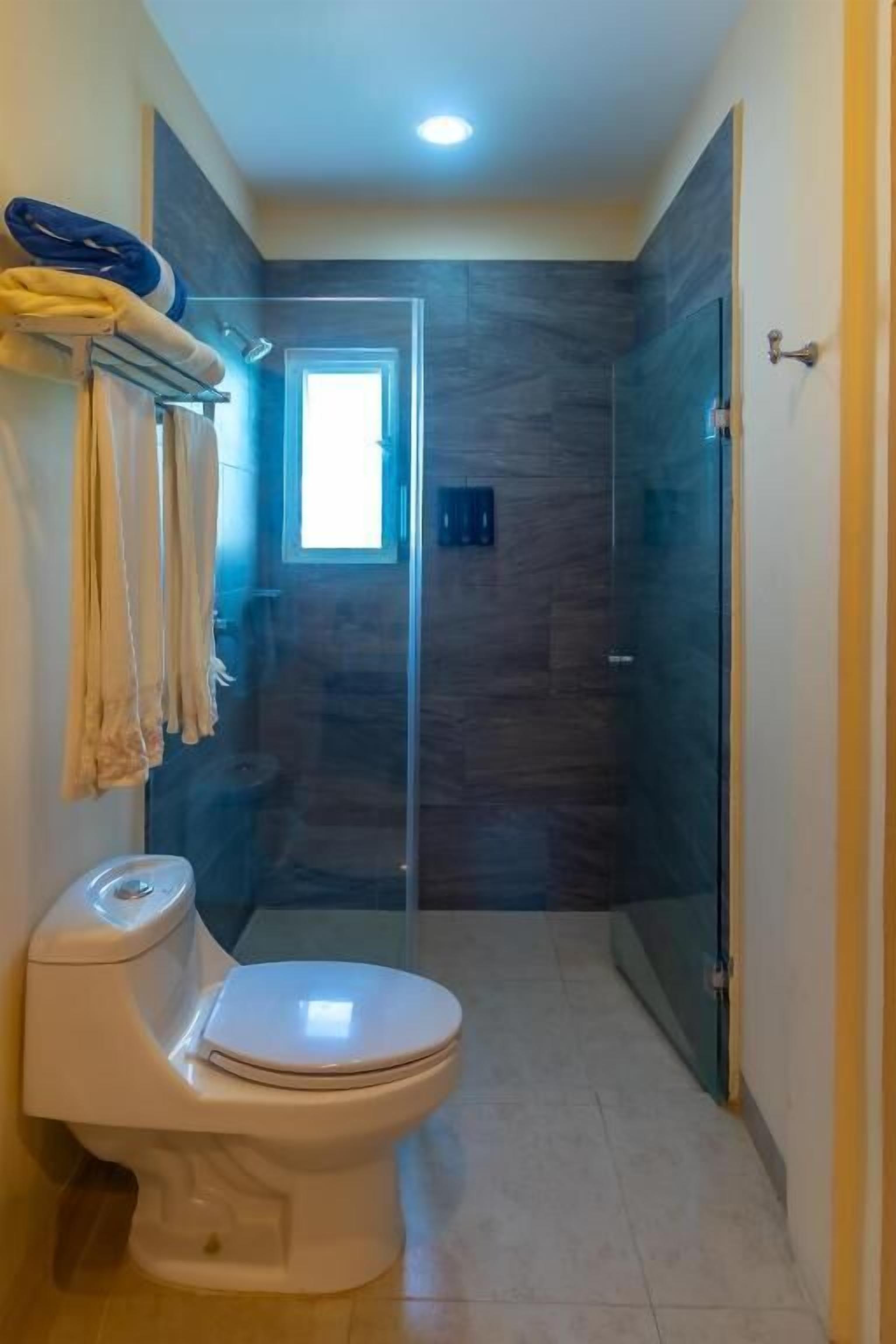 Ein modernes Badezimmer mit Toilette, einer Duschkabine aus Glas und einem kleinen Fenster.