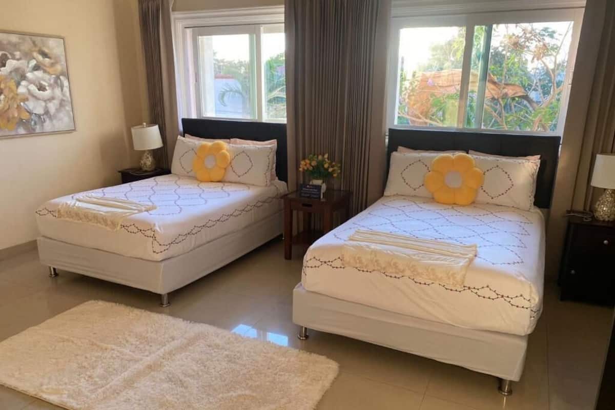 Une chambre d’hôtel avec deux lits simples, un grand tapis moelleux et une vue sur la verdure.