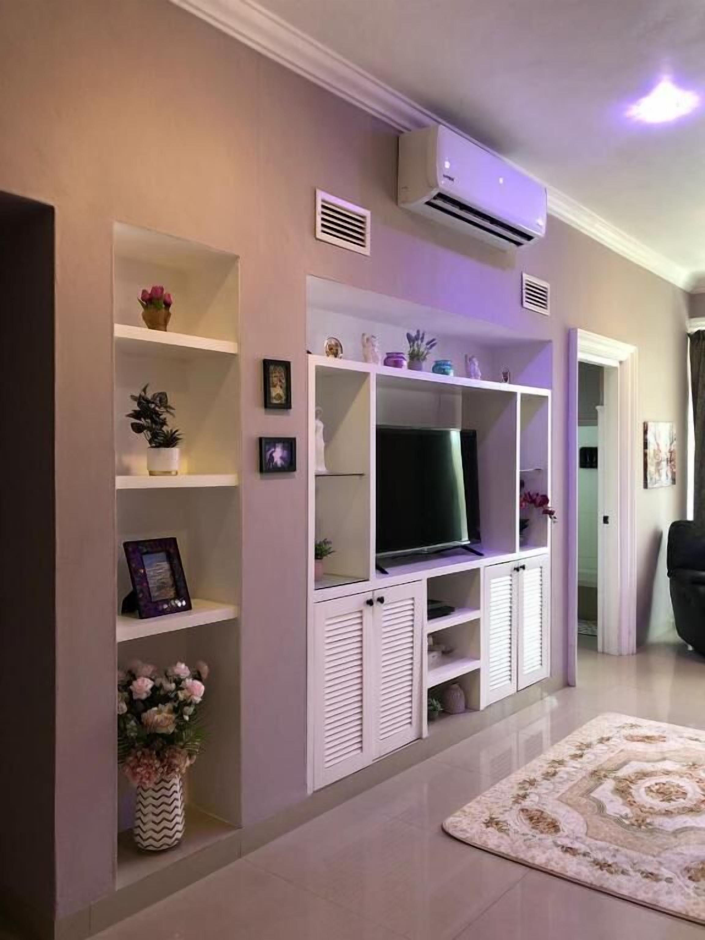 Una sala de estar con televisor de pantalla plana, estanterías empotradas y un tapete decorativo.