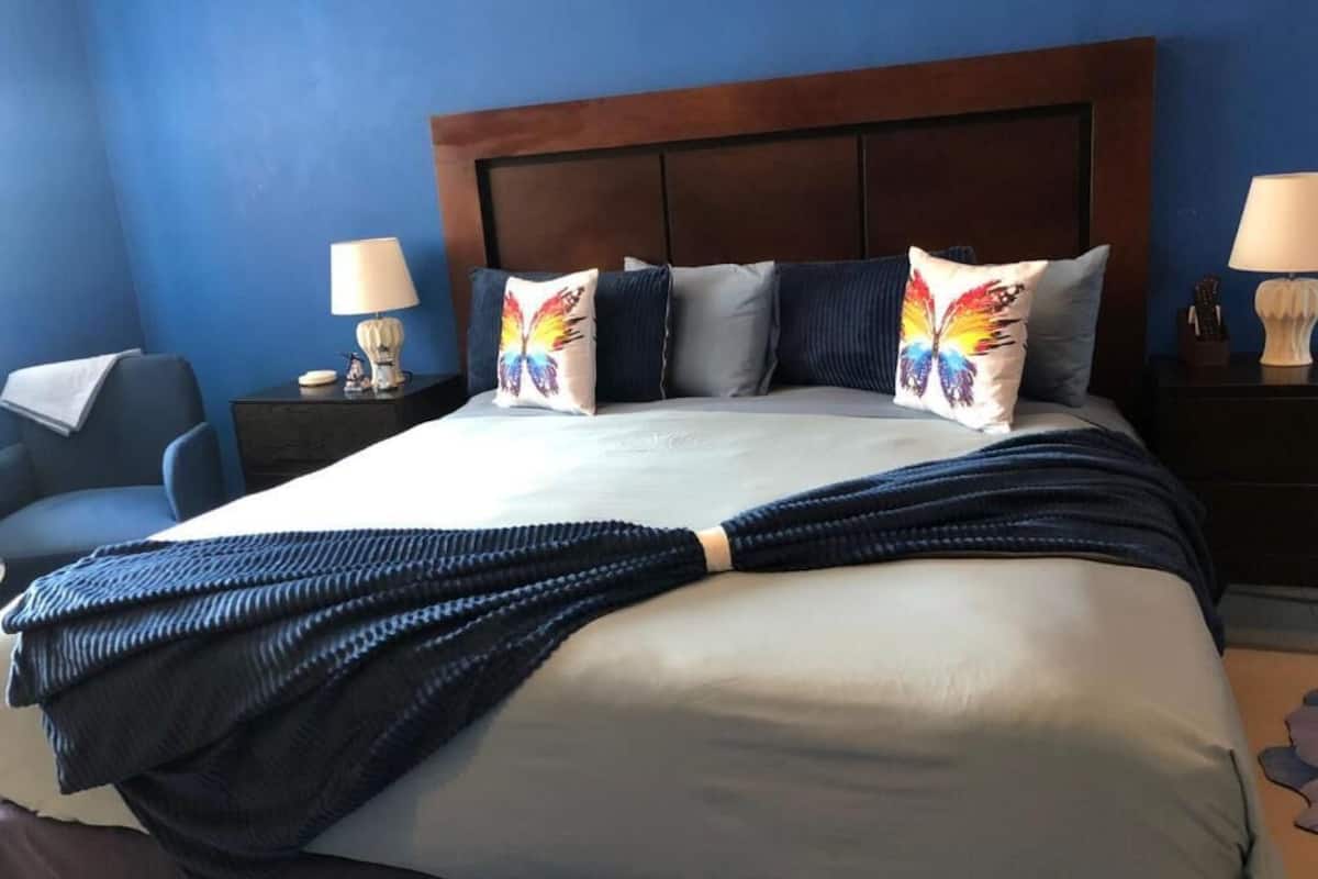 Une chambre d’hôtel avec un grand lit, une tête de lit en bois et deux tables de chevet avec des lampes.