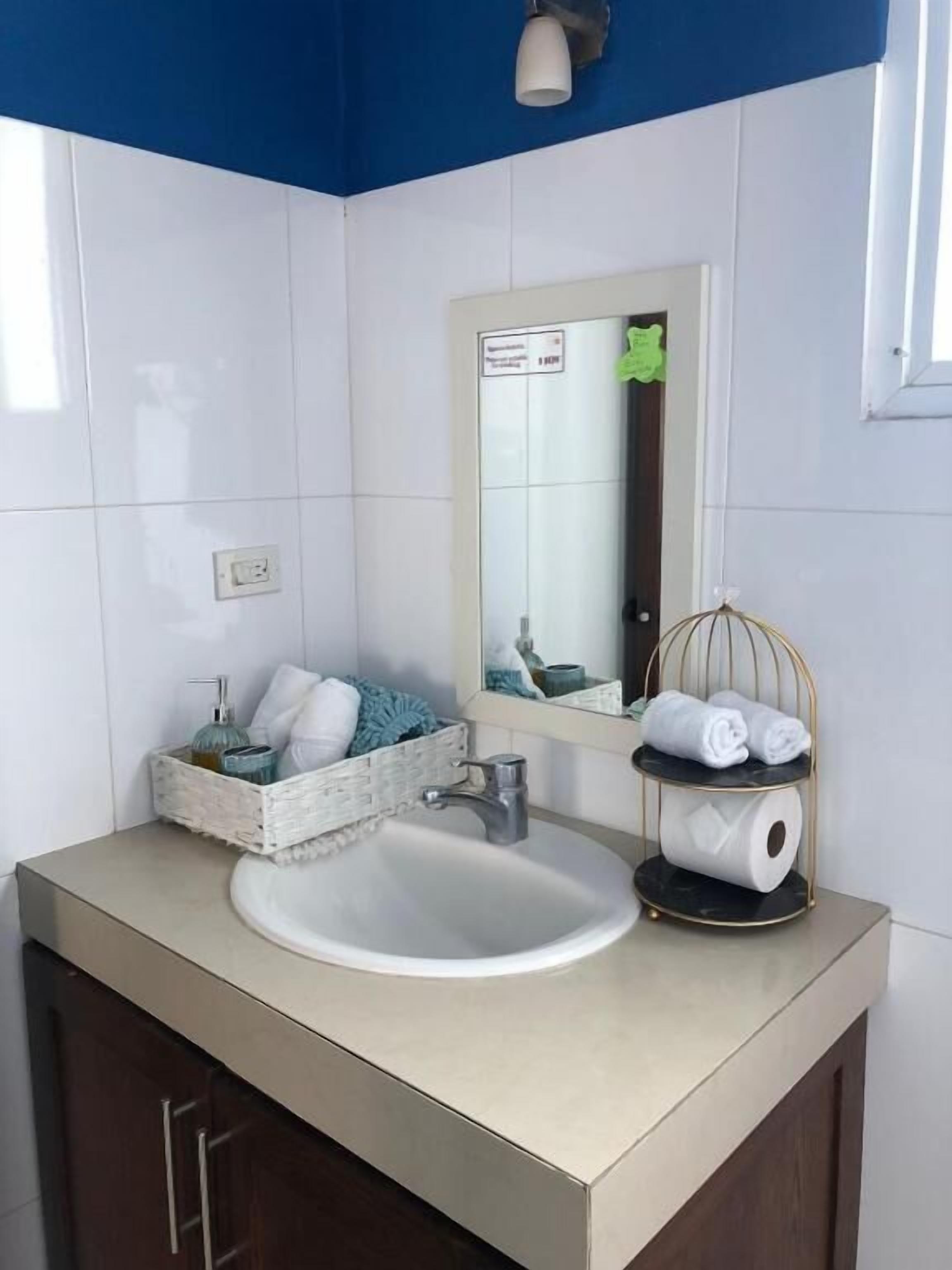 A bathroom with a white sink, a mirror, and a towel rack.