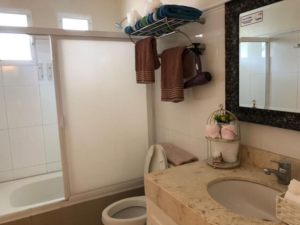 Une salle de bain comprenant une baignoire, un lavabo, un porte-serviettes avec des serviettes et une petite étagère avec des articles de toilette.