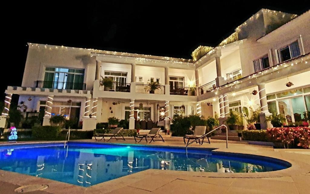 Um hotel com vários andares, piscina, área de estar ao ar livre e luzes de fada.