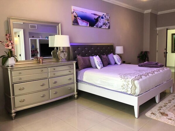 Un dormitorio con cama, cómoda y un espejo grande.