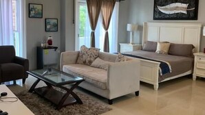 Una sala moderna con un sofá, una mesa de centro de vidrio, una cama y un escritorio.