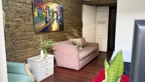 A living room with a brick wall, a sofa, a small table with a plant, and a painting. - Casa Cordoba (Bogotá)