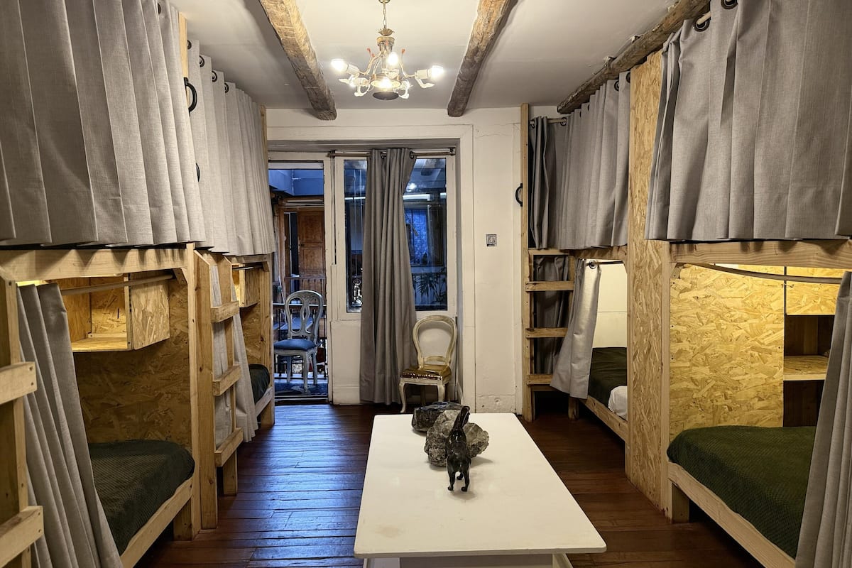 Ein Zimmer mit Etagenbetten, einem Tisch und einer Kristallleuchter.