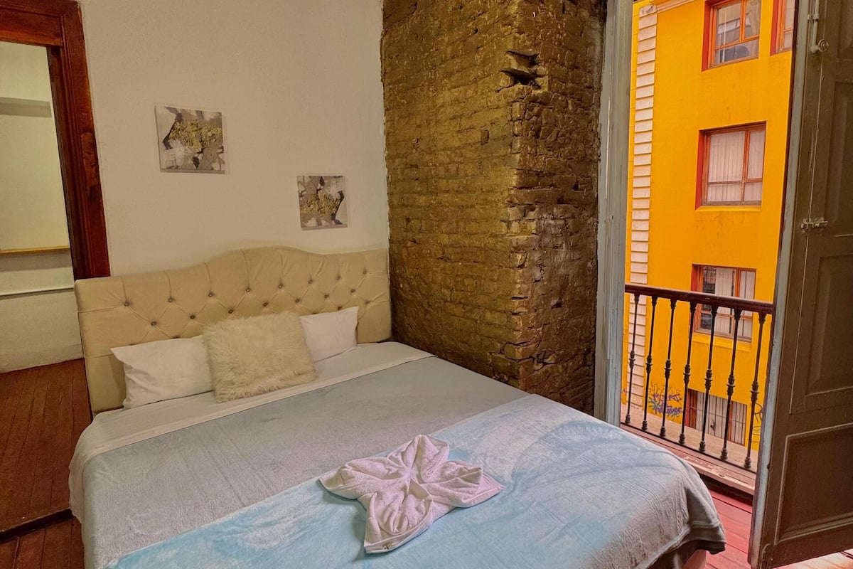 Ein Schlafzimmer mit einem Bett, einem Kopfteil, einer Holzwand und einem Balkon mit Geländer.