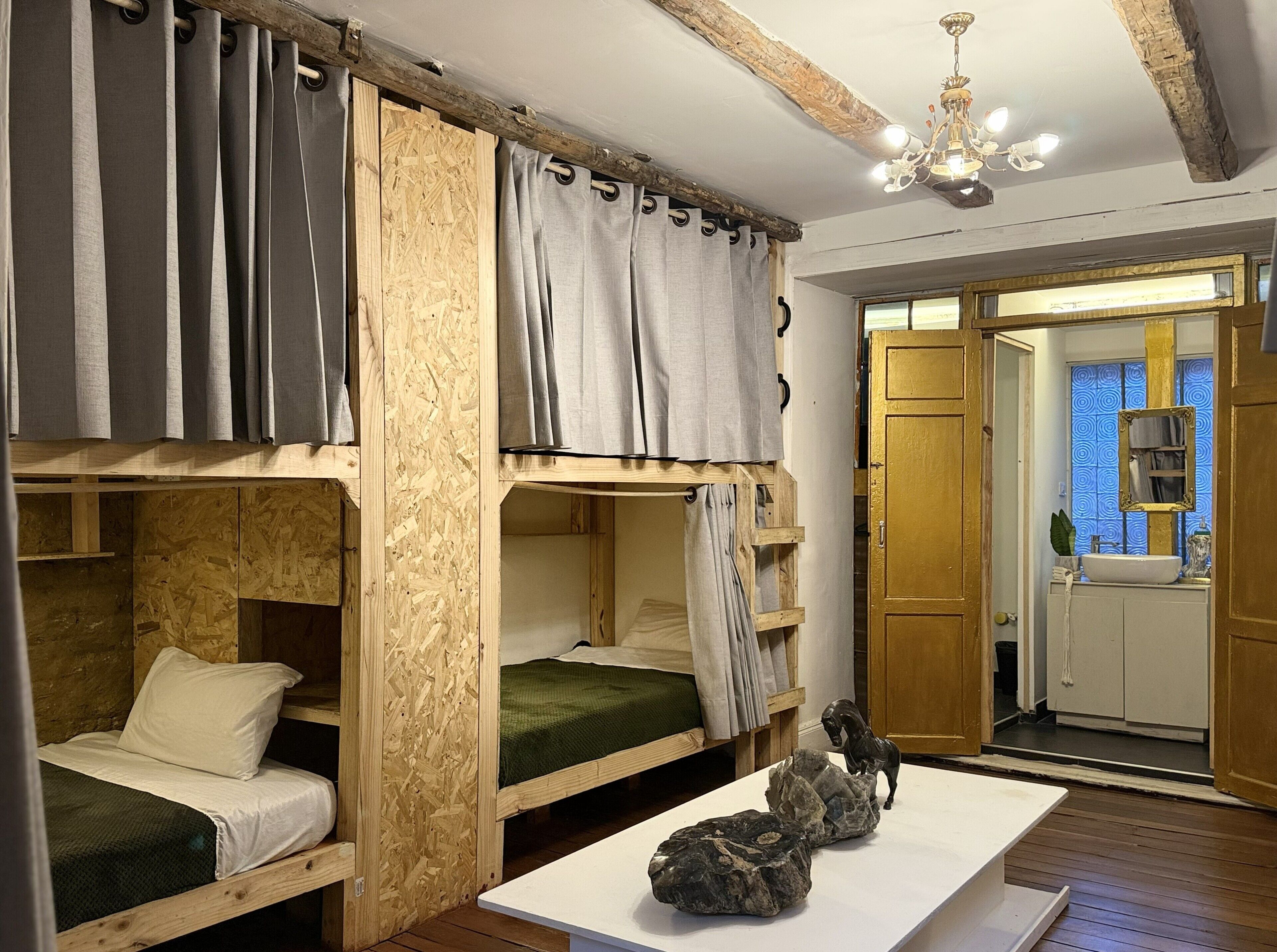 A bunk bed room with a wooden headboard, a small table with rocks, and a bathroom visible through an open door.