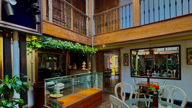 A spacious indoor area with a glass display case, wooden furniture, and a balcony with a railing. - Casa Cordoba (Bogotá)