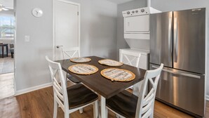 A modern kitchen with a stainless steel refrigerator, a built-in oven, and a dining table with four woven placemats.