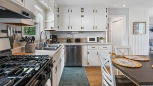 A modern kitchen with white cabinets, stainless steel appliances, and a dining area with a table and chairs.