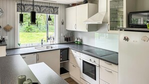 A modern kitchen with white cabinets, a black countertop, and a large window with a view of a garden. - Lovely home in Hemmet with WiFi (Hemmet)