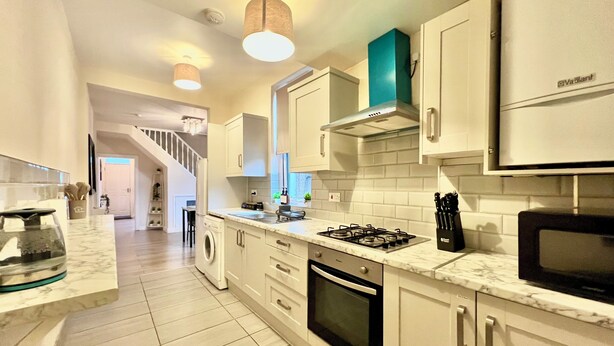A modern kitchen with white cabinetry, a gas stove, a microwave, and a built-in oven. - Spacious, Cosy & Modern Home w/ Parking , Wi-Fi and Garden (coventry west midlands)