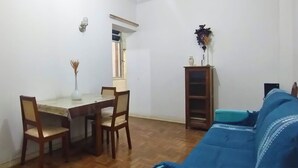 A room with a dining table, chairs, a blue sofa, a wooden cabinet, and a window. - Spacious 2-bedroom apartment in lovely Botafogo Rio de Janeiro with WiFi (Botafogo Rio de Janeiro)