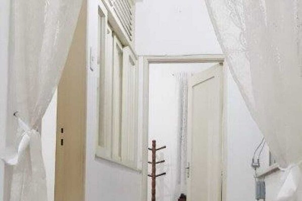 A narrow hallway with a coat rack and a door at the end.