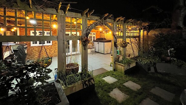 Un restaurante con terraza, fachada de ladrillo y luces colgantes.