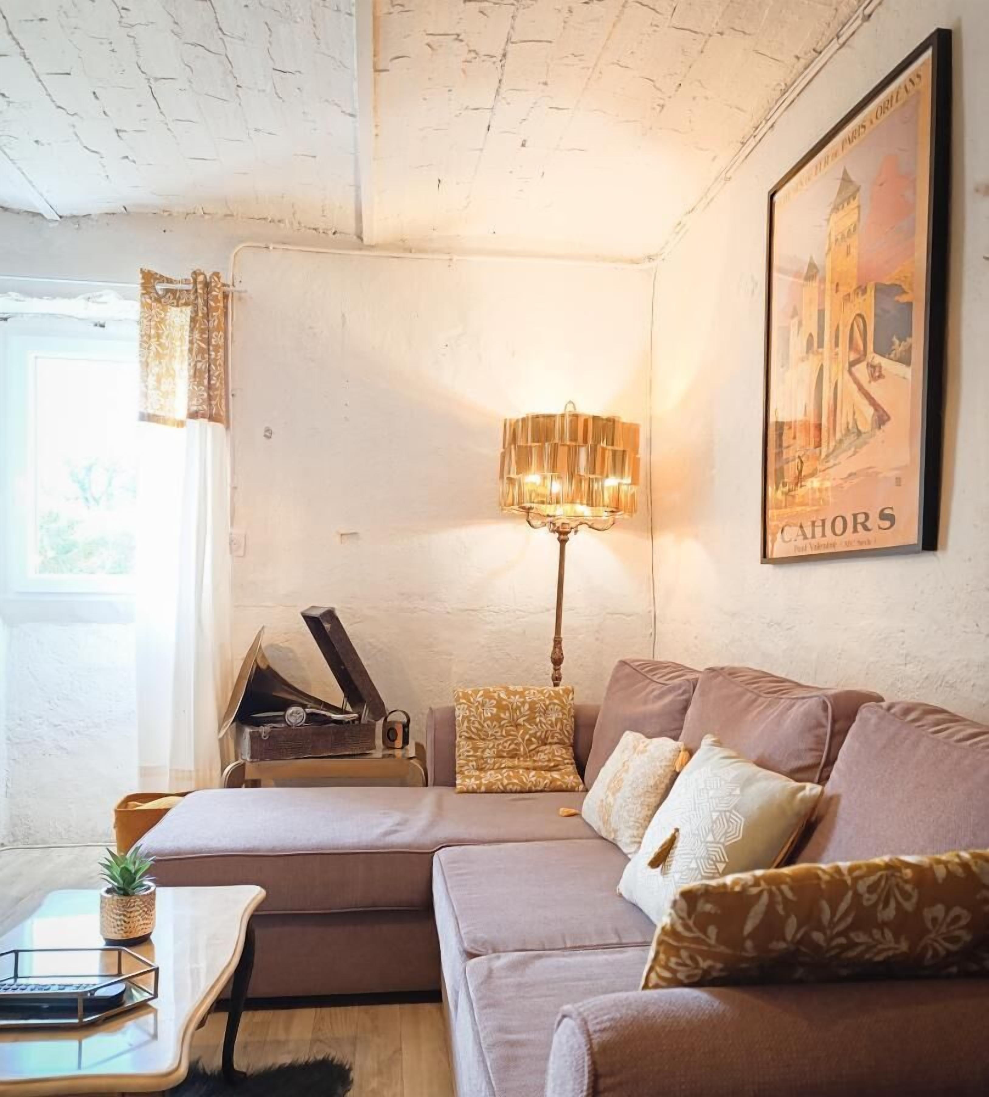 Uma sala de estar aconchegante com um sofá seccional, um abajur de chão, um piano e um quadro na parede.