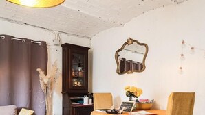 Una sala de estar acogedora con un sofá, una mesa de comedor con sillas, un aparador y un espejo en la pared.
