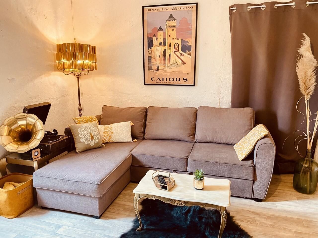 Ein gemütliches Wohnzimmer mit einer Eckcouch, einem Vintage-Gramophon, einer Lampe und einem gerahmten Poster an der Wand.