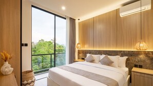 A modern bedroom with a large bed, wooden headboard, and a view of greenery through a balcony.